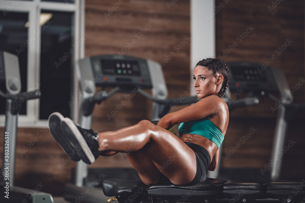 Slim dark-haired girl dressed in sports clothes doing exercises for the press on the mat for fitness with fitness ball in the gym Slim dark-haired girl dressed in sports clothes doing exercises for the press on the mat for fitness with fitness ball in the gym