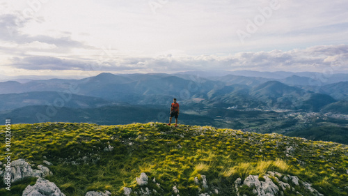 Aerial view of a trail running man standing on the ridge of a mountain