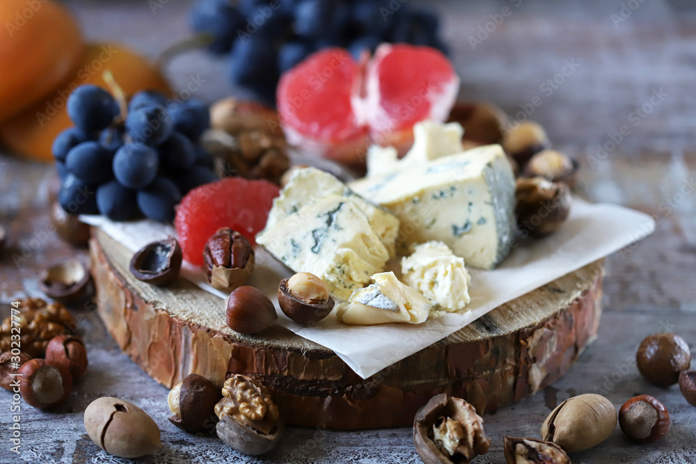 Selective focus. Beautiful cheese set with nuts, blue grapes and grape fruit. Keto snack. Healthy snack with wine.