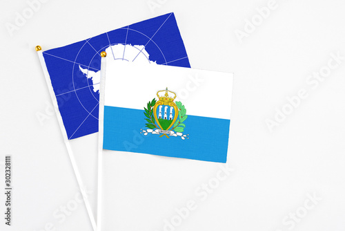 San Marino and Antarctica stick flags on white background. High quality fabric, miniature national flag. Peaceful global concept.White floor for copy space.