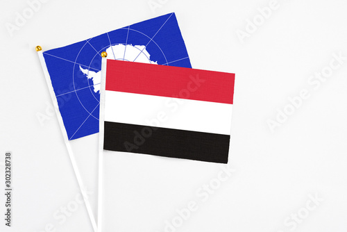 Yemen and Antarctica stick flags on white background. High quality fabric, miniature national flag. Peaceful global concept.White floor for copy space.