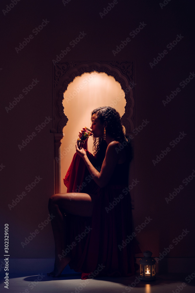 Sexy muslim female sitting on a decorated moroccan window at a hotel resort drinking traditional tea. Travel around the world. Islamic culture and religion. Feminist woman with arabian culture concept