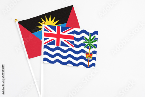 British Indian Ocean Territory and Antigua and Barbuda stick flags on white background. High quality fabric, miniature national flag. Peaceful global concept.White floor for copy space. photo