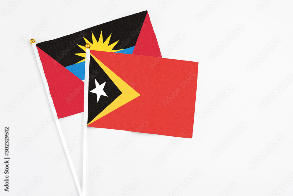 East Timor and Antigua and Barbuda stick flags on white background. High quality fabric, miniature national flag. Peaceful global concept.White floor for copy space. East Timor and Antigua and Barbuda stick flags on white background. High quality fabric, miniature national flag. Peaceful global concept.White floor for copy space.