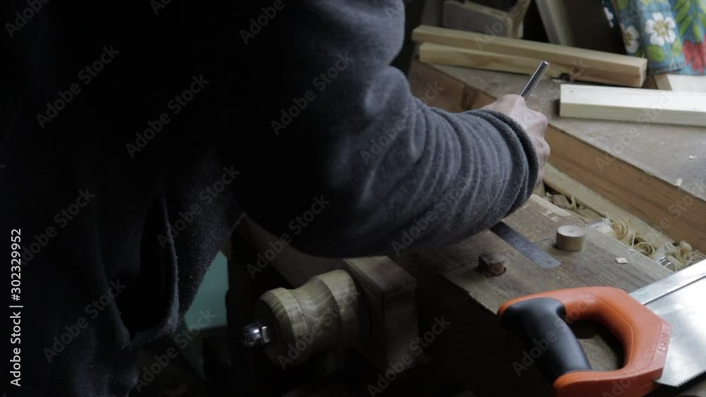 Male carpenter attaching wooden plank to the pine shelf to check if it suits by measure and marking it with a blade cut Male carpenter attaching wooden plank to the pine shelf to check if it suits by measure and marking it with a blade cut