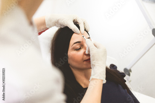 Сosmetologist doctor injects botox into the patient's forehead