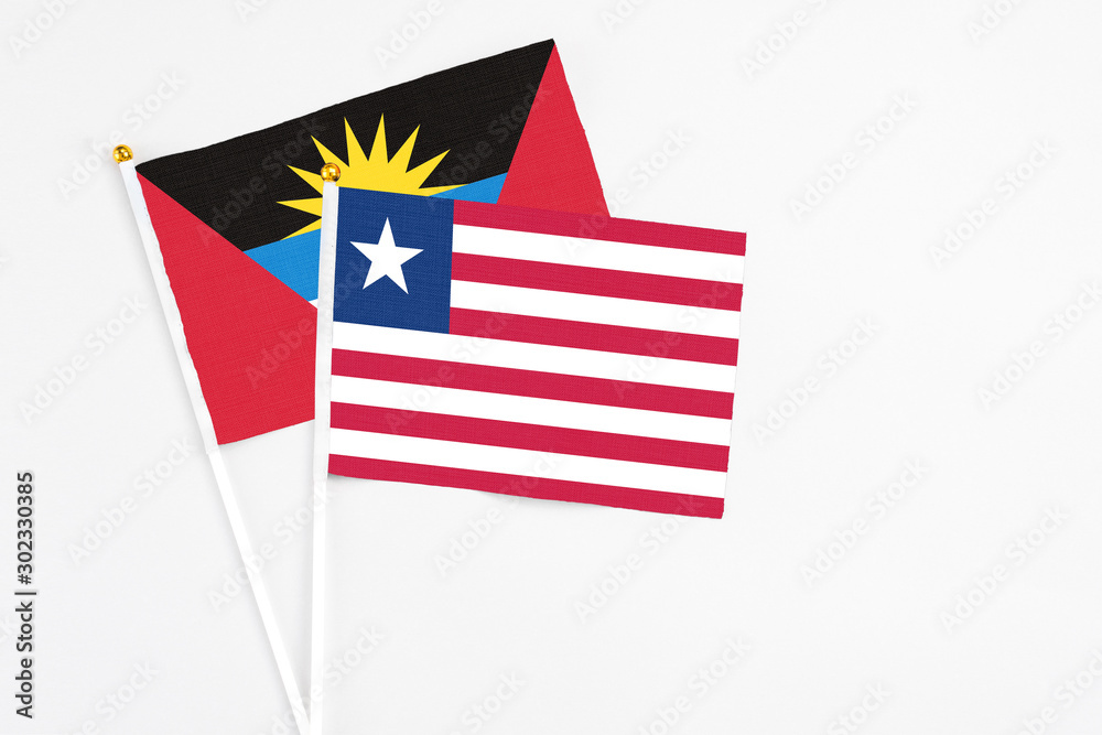 Liberia and Antigua and Barbuda stick flags on white background. High quality fabric, miniature national flag. Peaceful global concept.White floor for copy space. Liberia and Antigua and Barbuda stick flags on white background. High quality fabric, miniature national flag. Peaceful global concept.White floor for copy space.