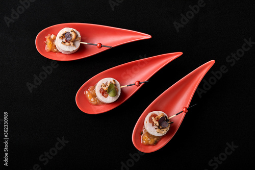 Fototapeta Naklejka Na Ścianę i Meble -  Goose liver pate, foie gras, served on black stone in Japanese red spoons. Paste served with jam and nuts. Fusion food concept, low key, copy space.