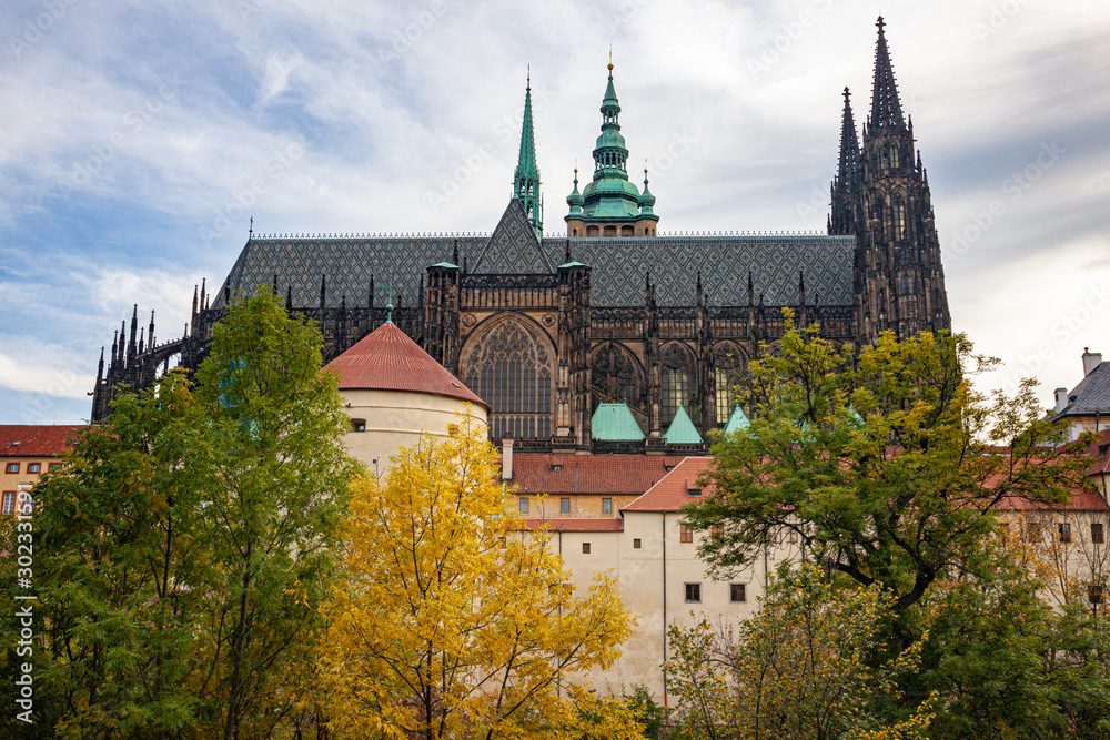 The gothic towers of St. Vitus Cathedral behind old city walls and gold auteumn trees at Prague, Chech republic