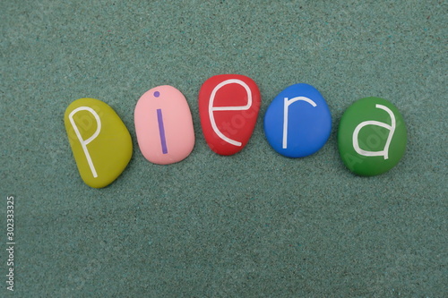 Piera, female given name composed with multi colored stone letters over green sand photo