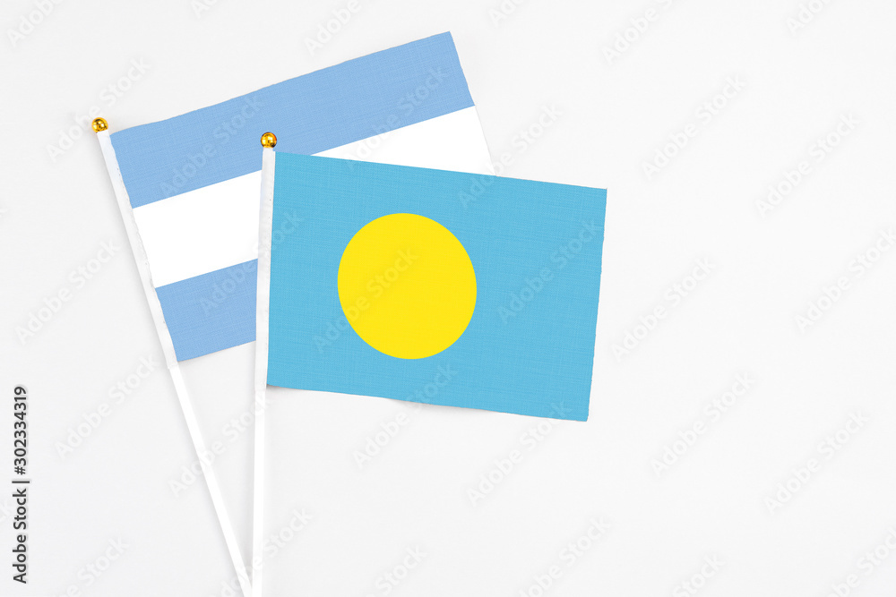 Palau and Argentina stick flags on white background. High quality fabric, miniature national flag. Peaceful global concept.White floor for copy space. Palau and Argentina stick flags on white background. High quality fabric, miniature national flag. Peaceful global concept.White floor for copy space.