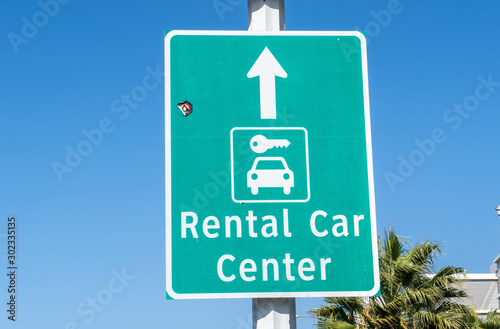 Sign with an arrow pointing straight to a rental car center