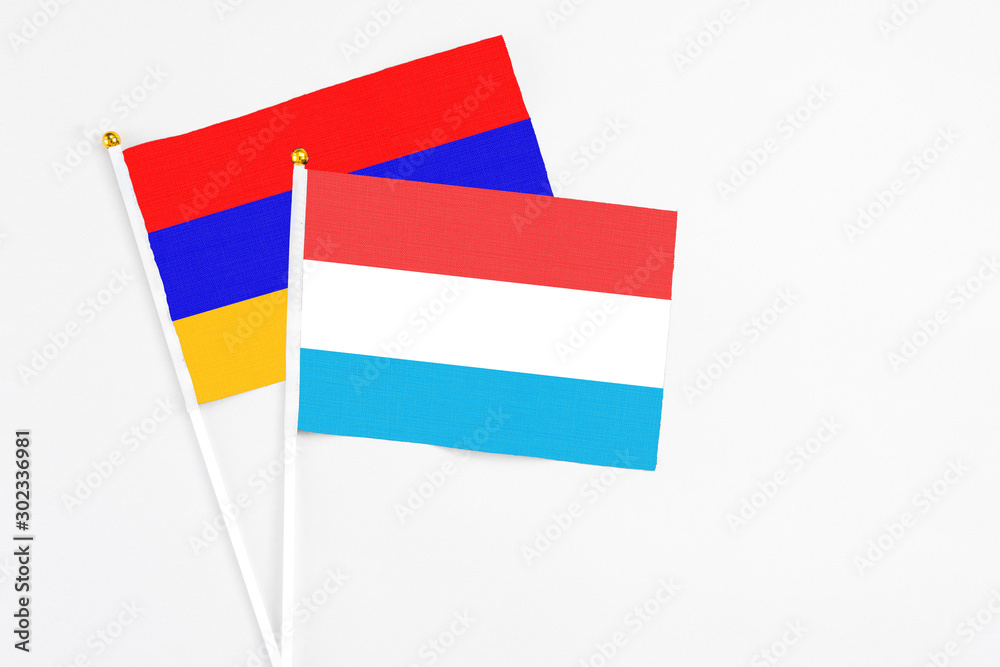Luxembourg and Armenia stick flags on white background. High quality fabric, miniature national flag. Peaceful global concept.White floor for copy space.