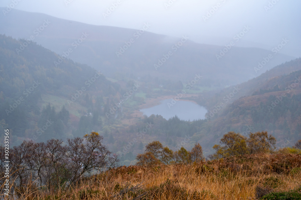 Glendalough Lower lake from the top of Glenealo valley, Wicklow way, County Wicklow, Ireland. Autumn hike during foggy weather and mist.