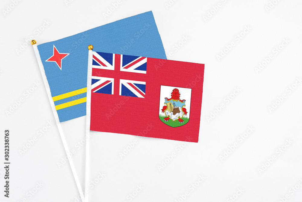 Fototapeta premium Bermuda and Aruba stick flags on white background. High quality fabric, miniature national flag. Peaceful global concept.White floor for copy space.