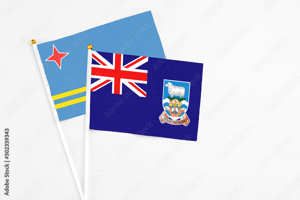 Fototapeta premium Falkland Islands and Aruba stick flags on white background. High quality fabric, miniature national flag. Peaceful global concept.White floor for copy space.