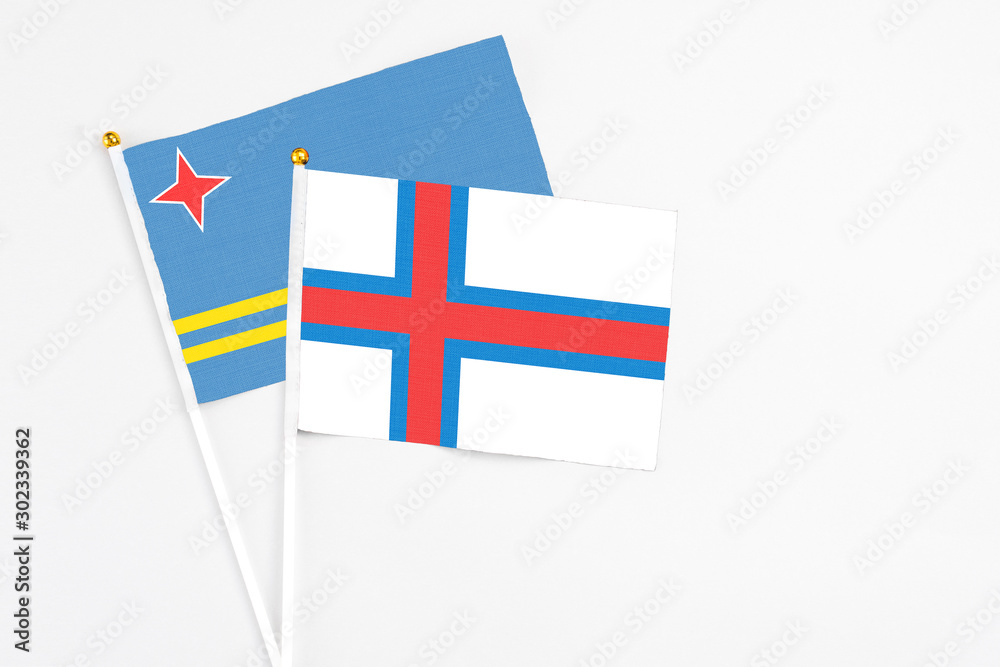 Faroe Islands and Aruba stick flags on white background. High quality fabric, miniature national flag. Peaceful global concept.White floor for copy space.