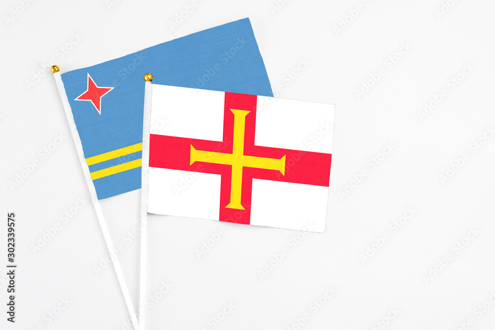 Guernsey and Aruba stick flags on white background. High quality fabric, miniature national flag. Peaceful global concept.White floor for copy space.