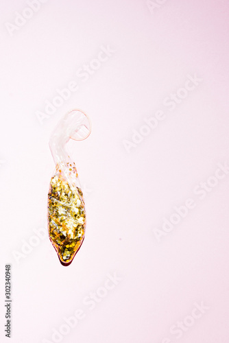 Condom full of golden paillettes  over an pink  background, new year theme party with a  bit of spice, couple love emotional conceptual image,