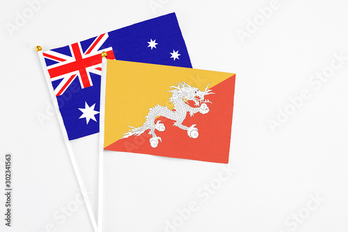Bhutan and Australia stick flags on white background. High quality fabric, miniature national flag. Peaceful global concept.White floor for copy space.
