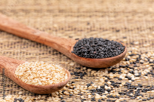 Wooden spoon full of both healthy sesame and black sesame seeds