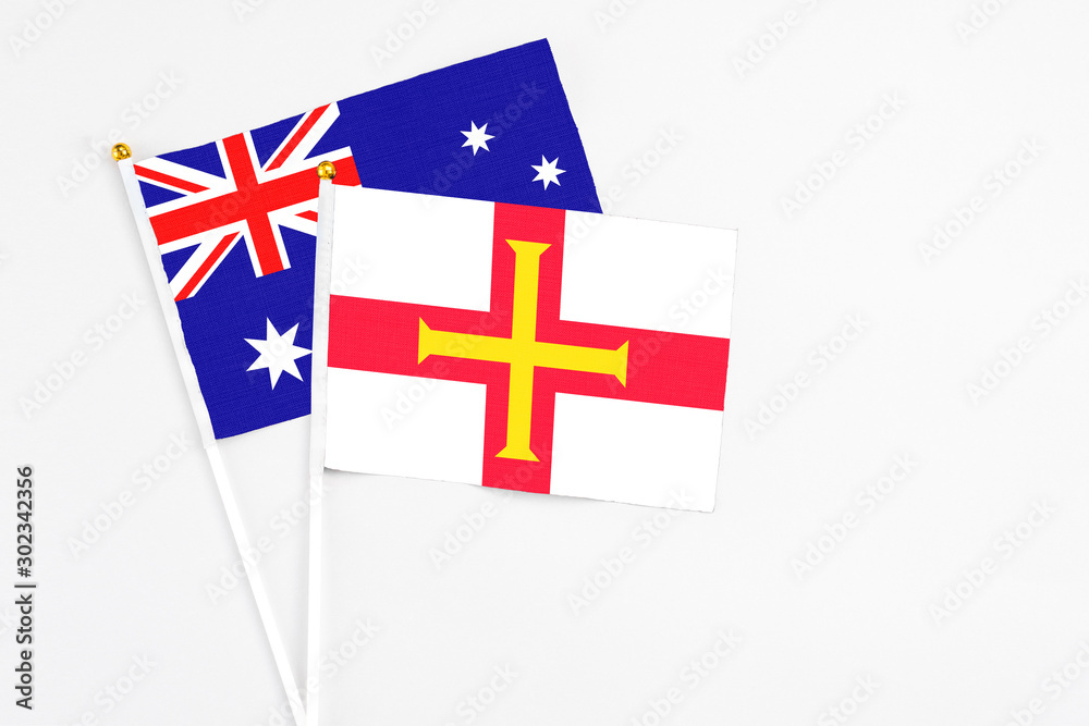 Guernsey and Australia stick flags on white background. High quality fabric, miniature national flag. Peaceful global concept.White floor for copy space.