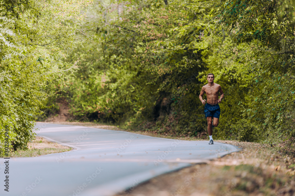 Runner athlete running on forest trail. Man fitness jogging workout wellness concept