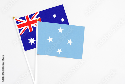 Micronesia and Australia stick flags on white background. High quality fabric, miniature national flag. Peaceful global concept.White floor for copy space. photo