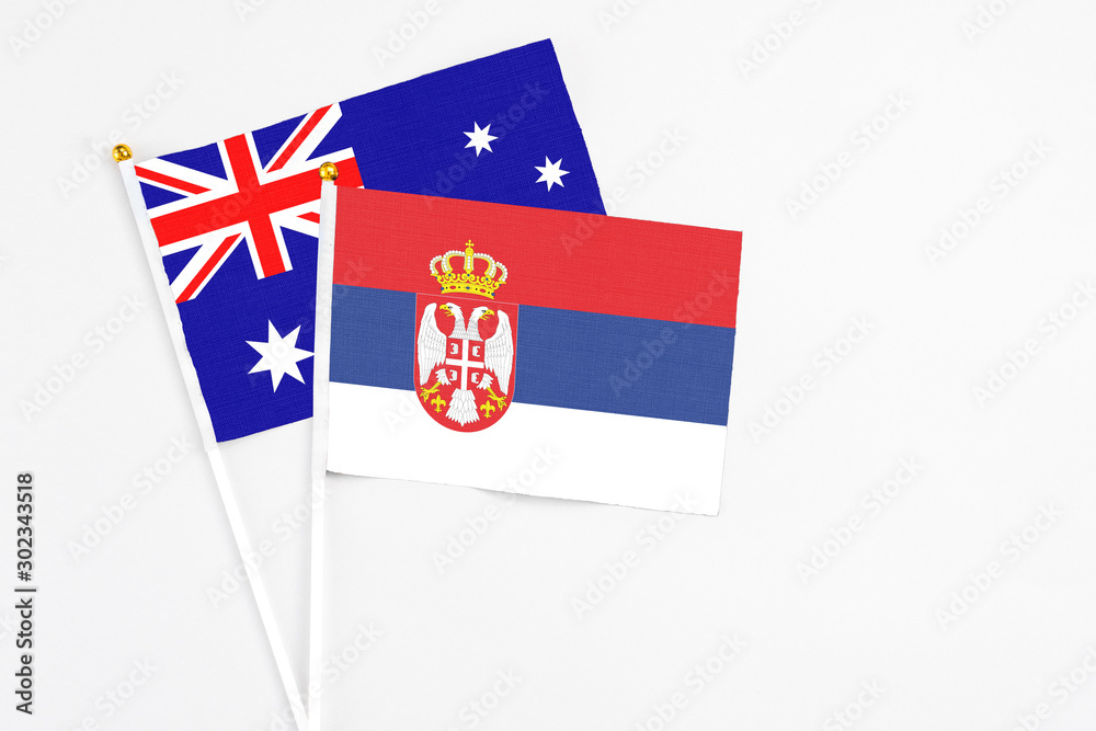 Fototapeta premium Serbia and Australia stick flags on white background. High quality fabric, miniature national flag. Peaceful global concept.White floor for copy space.