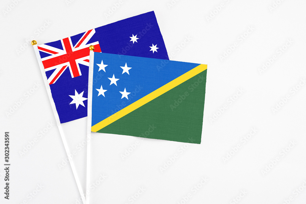 Solomon Islands and Australia stick flags on white background. High quality fabric, miniature national flag. Peaceful global concept.White floor for copy space. Solomon Islands and Australia stick flags on white background. High quality fabric, miniature national flag. Peaceful global concept.White floor for copy space.