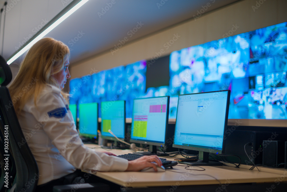 Female security guard sitting and monitoring modern CCTV cameras in a surveillance room. Female security guard sitting and monitoring modern CCTV cameras in a surveillance room.