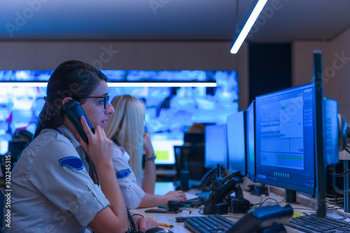 Technical Operator Works at His Workstation with Multiple Displays while talking on the phone, Security guards working on multiple monitors...