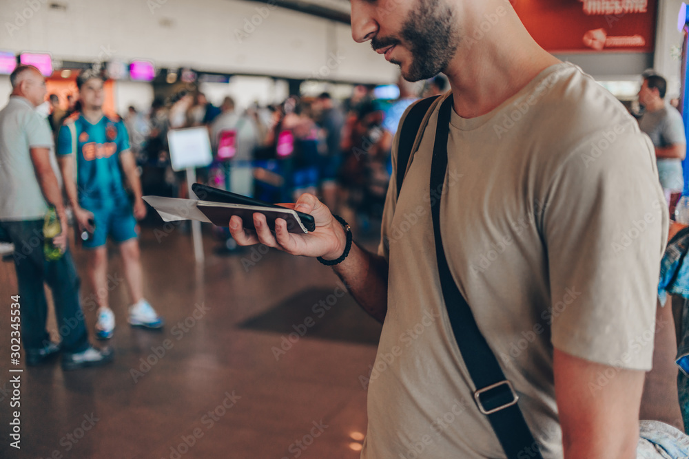 Fototapeta premium Happy traveler man is waiting for his flight at the airport