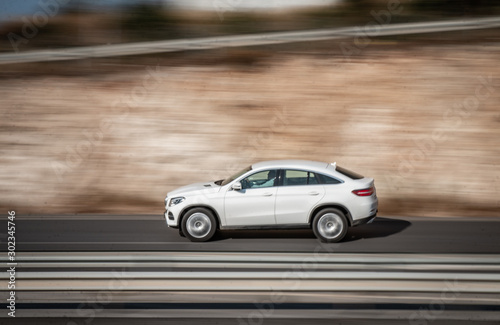 White car moving fast along the street on a motion blurred background. Car driving on freeway, motion blur. Luxury-car. © Artem