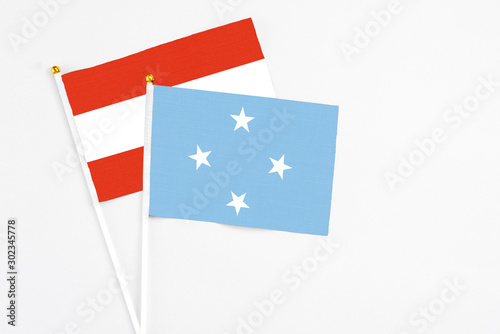 Micronesia and Austria stick flags on white background. High quality fabric, miniature national flag. Peaceful global concept.White floor for copy space. photo