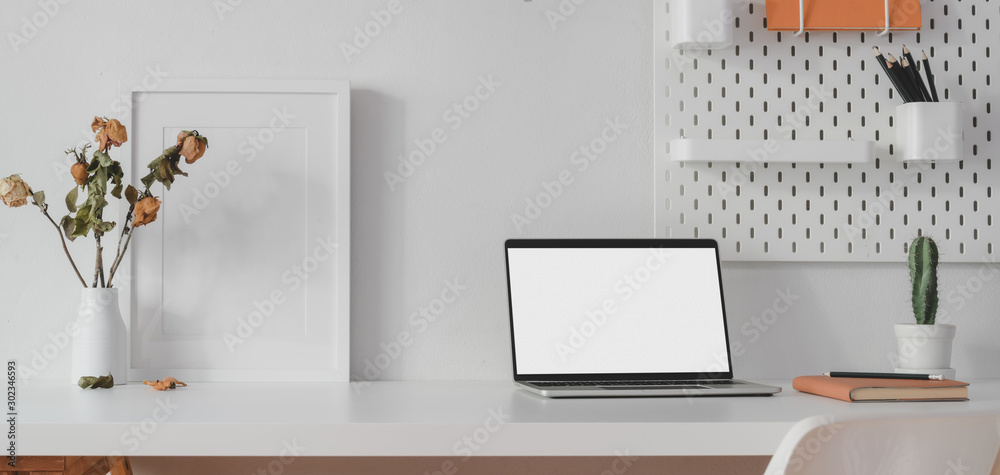 Modern workspace with open blank screen laptop computer and mock up frame with decorations - obrazy, fototapety, plakaty 