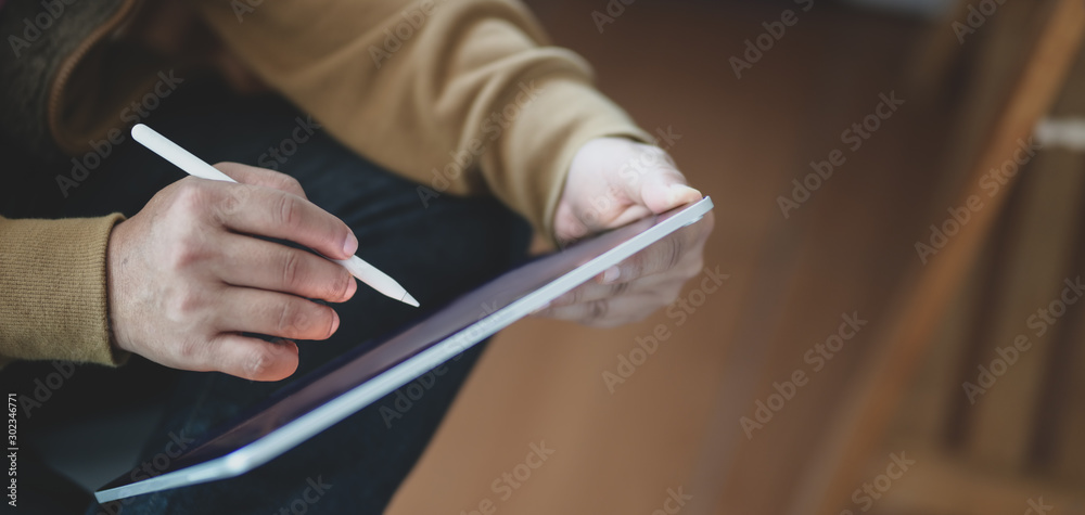 Close-up view of freelancer working on his project while writing on blank screen tablet