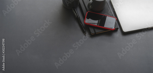 Top view of dark stylish workplace with laptop computer and office supplies on black table