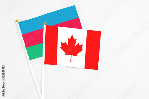 Canada and Azerbaijan stick flags on white background. High quality fabric, miniature national flag. Peaceful global concept.White floor for copy space.