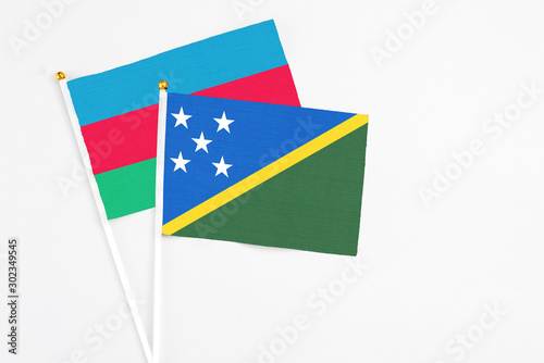 Solomon Islands and Azerbaijan stick flags on white background. High quality fabric  miniature national flag. Peaceful global concept.White floor for copy space.