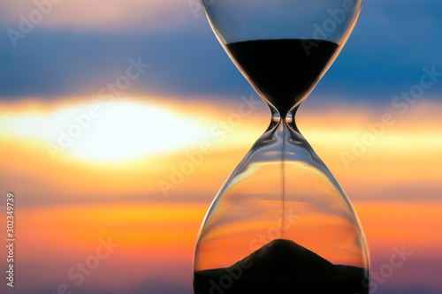 Hourglass on the background of a sunset. The value of time in life. An eternity.. photo