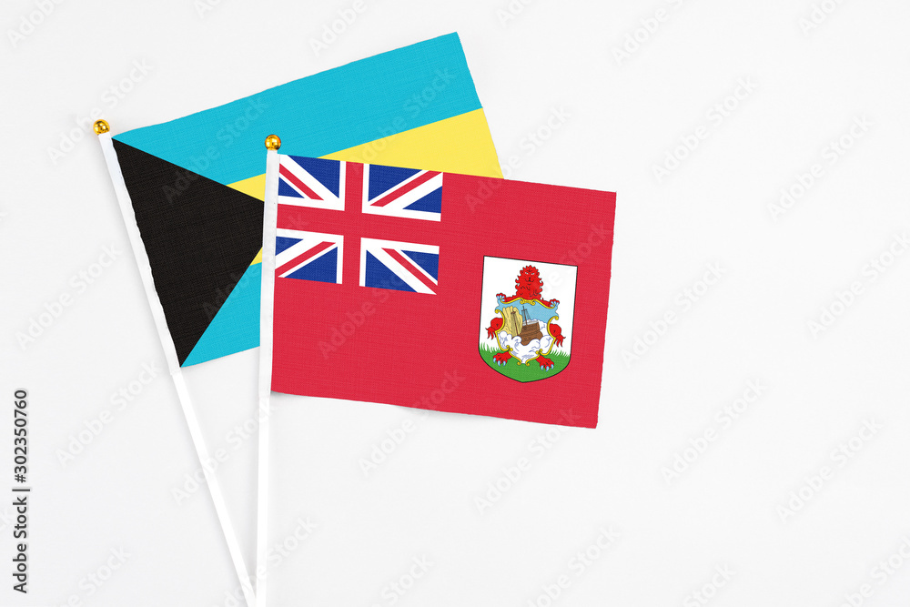 Fototapeta premium Bermuda and Bahamas stick flags on white background. High quality fabric, miniature national flag. Peaceful global concept.White floor for copy space.