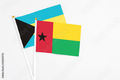 Guinea Bissau and Bahamas stick flags on white background. High quality fabric  miniature national flag. Peaceful global concept.White floor for copy space.