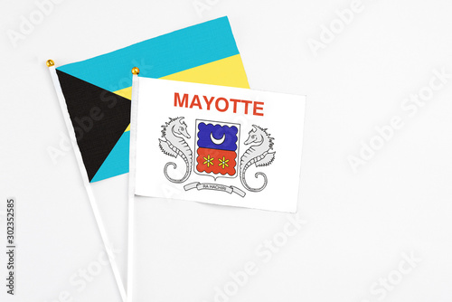 Mayotte and Bahamas stick flags on white background. High quality fabric, miniature national flag. Peaceful global concept.White floor for copy space.