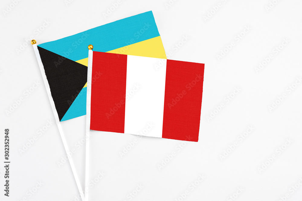 Peru and Bahamas stick flags on white background. High quality fabric, miniature national flag. Peaceful global concept.White floor for copy space.