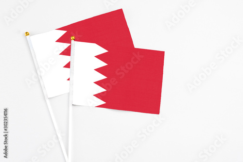 Bahrain and Bahrain stick flags on white background. High quality fabric, miniature national flag. Peaceful global concept.White floor for copy space.