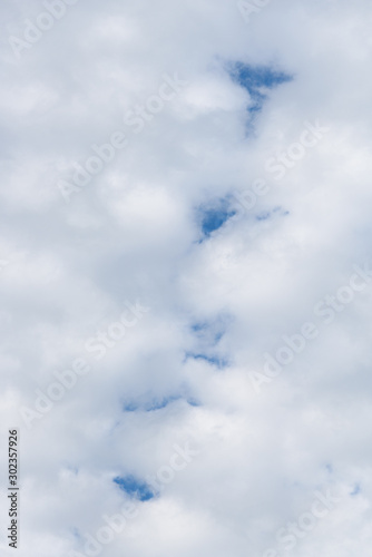 Small puffy white cloud pattern with glimpses of blue sky as a nature background