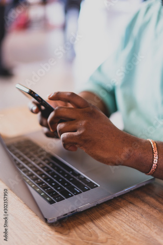 man texting on phone with laptop