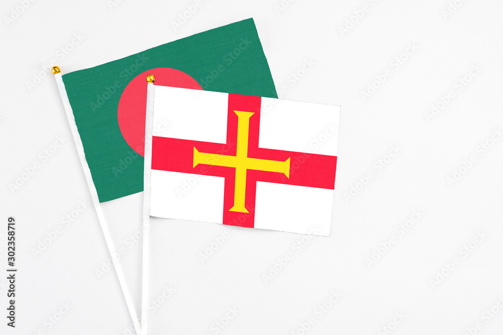 Guernsey and Bangladesh stick flags on white background. High quality fabric, miniature national flag. Peaceful global concept.White floor for copy space.