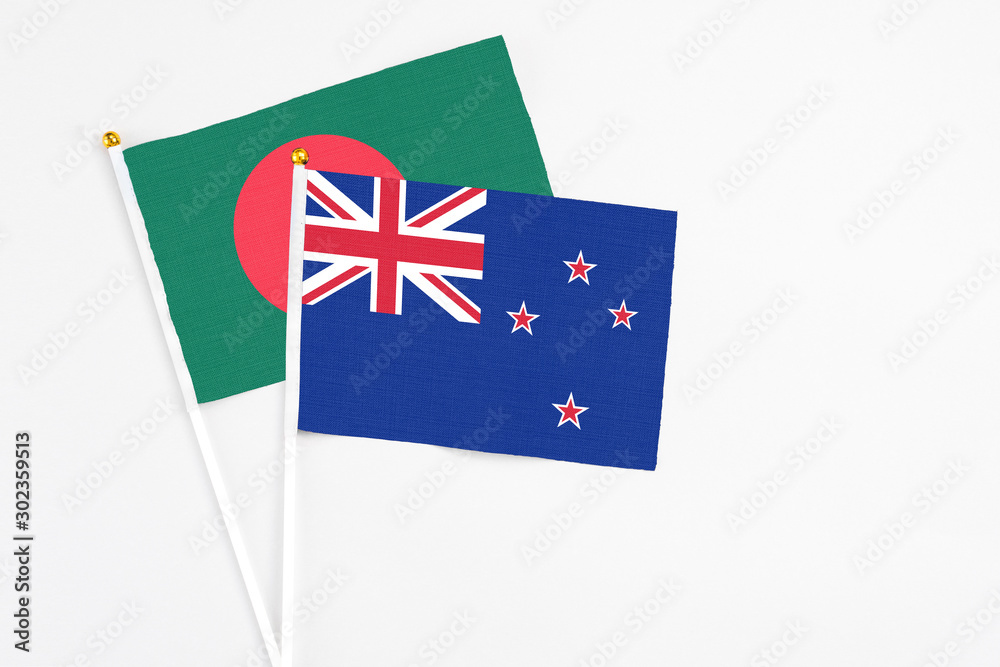 Fototapeta premium New Zealand and Bangladesh stick flags on white background. High quality fabric, miniature national flag. Peaceful global concept.White floor for copy space.
